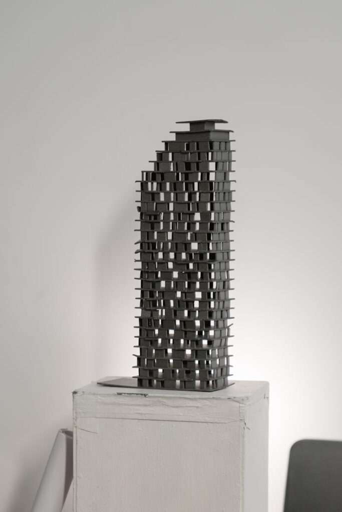 pexels photo 6615202 Abstract architectural model in gray silhouette on a white pedestal, studio background.